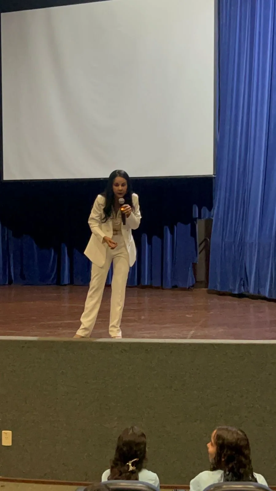 Dra. Genaina Morais em fala ao microfone durante palestra no palco